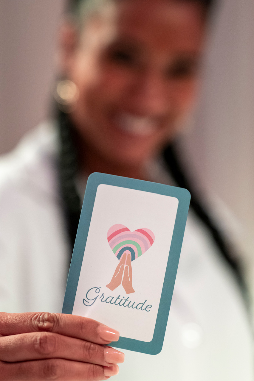 Victoria holding a Gratitude oracle card — a symbol of the heart we bring to every session